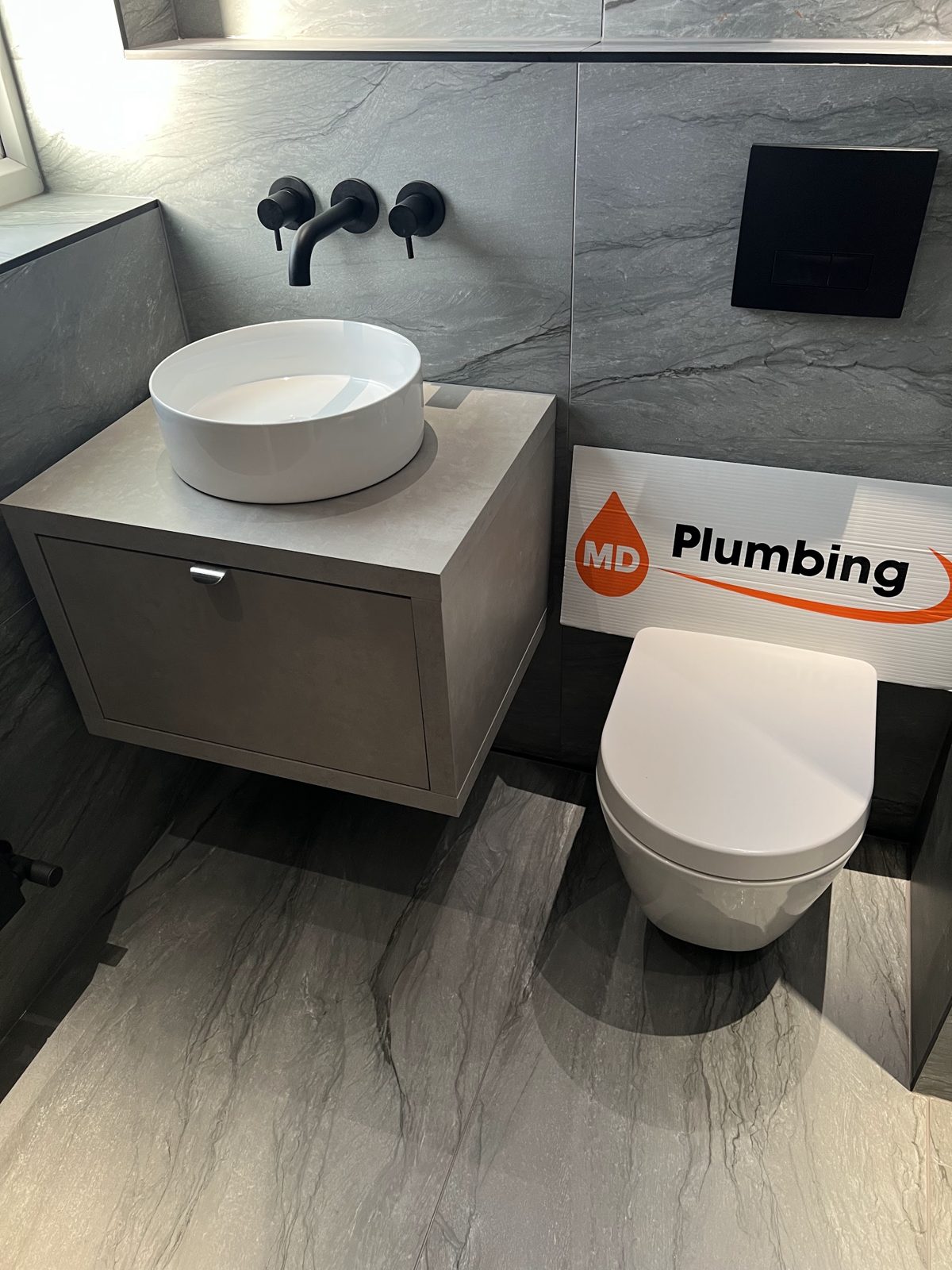 Round vessel basin on a floating unit with matt black wall taps