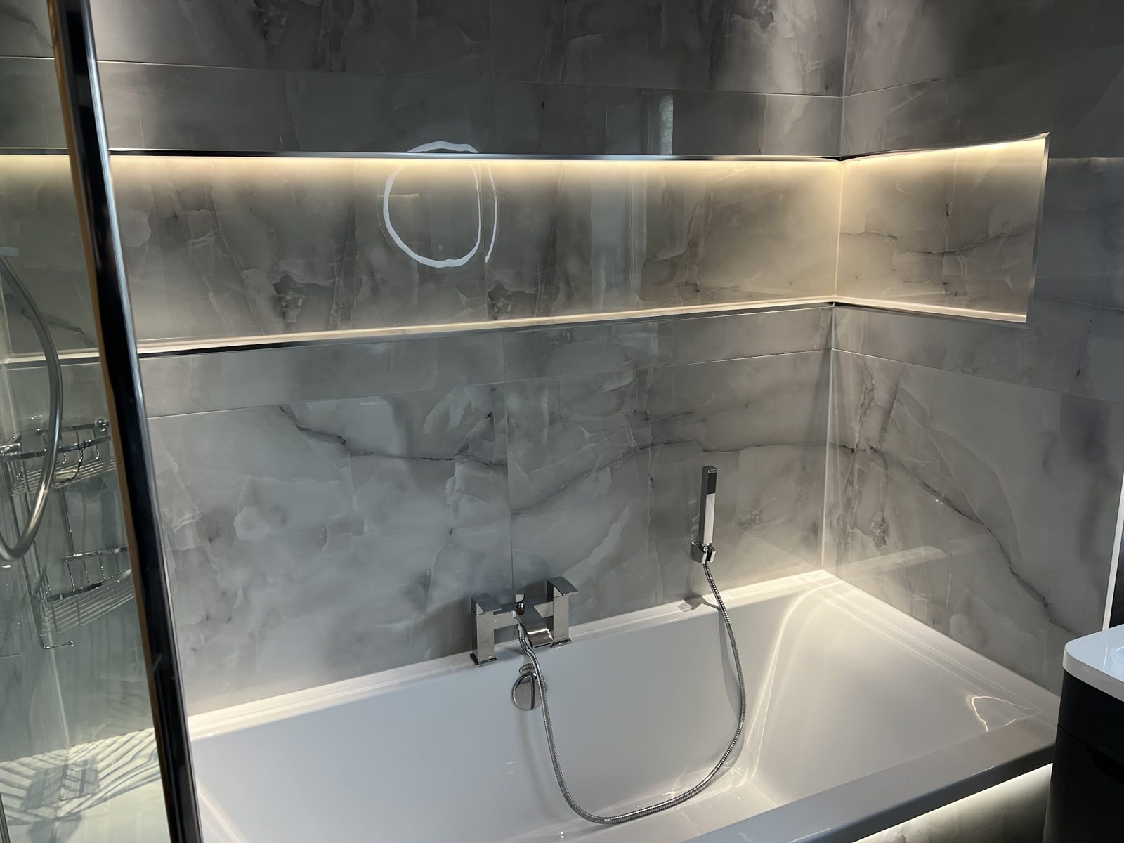 Bath with a long illuminated shelf above it