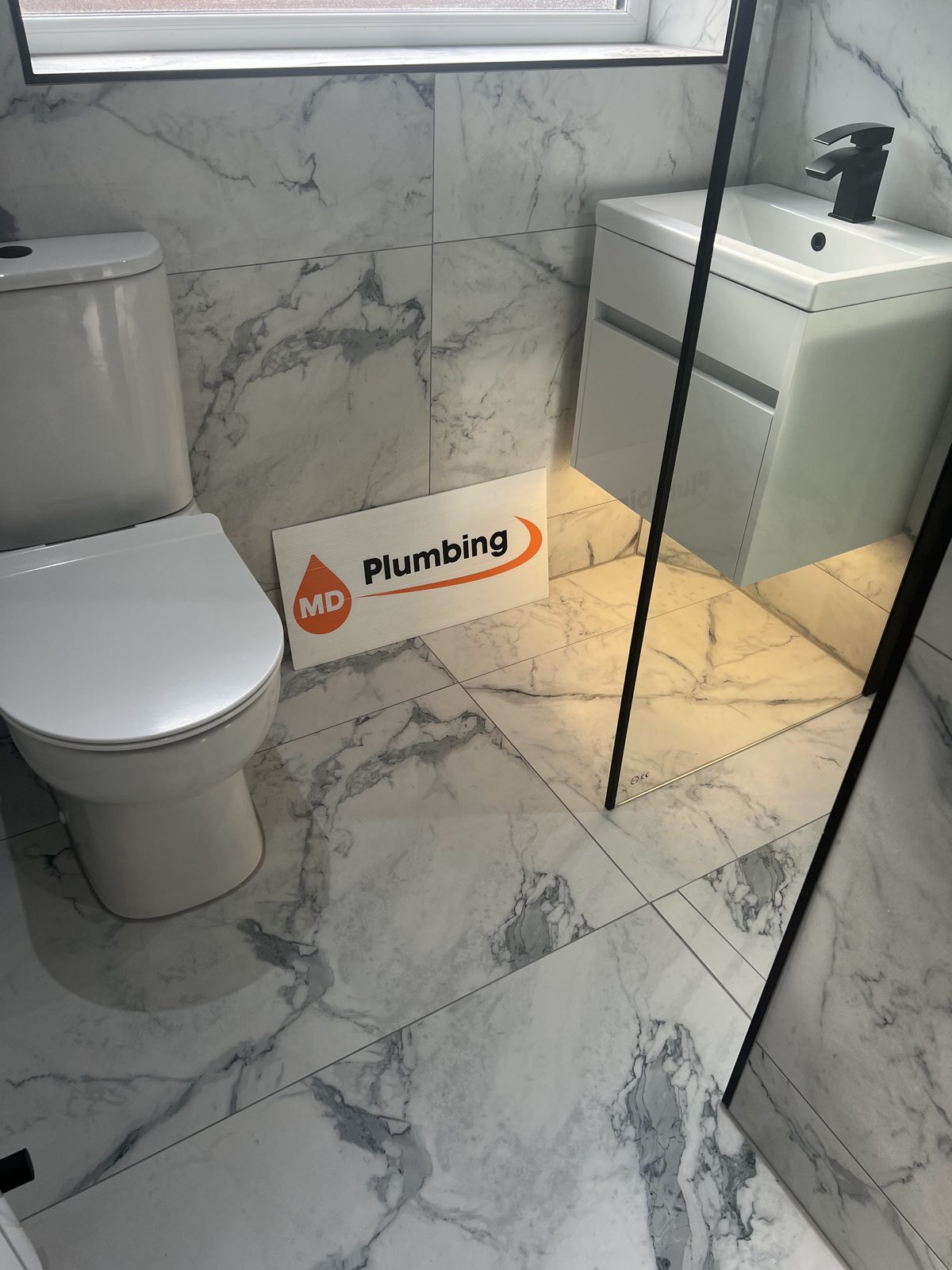 Grey marble bathroom with a white vanity unit and black shower screen