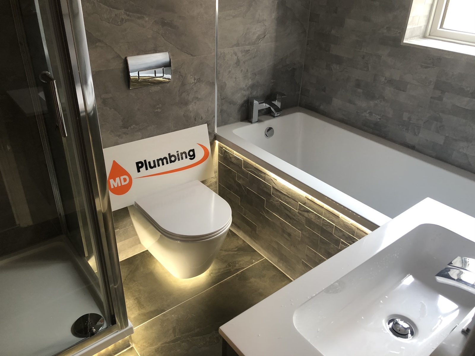Bath with an LED-lit plinth and wall-hung toilet