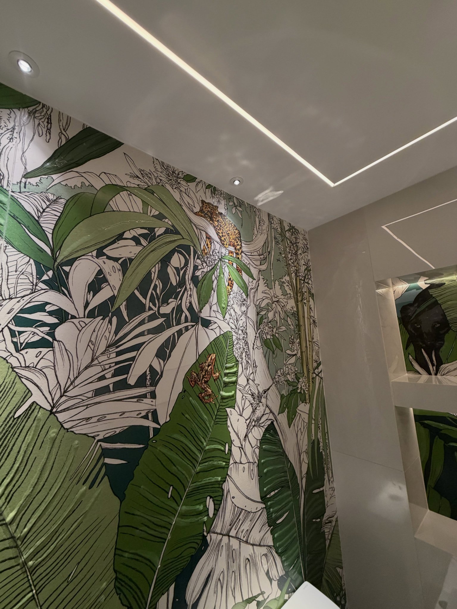 Tropical leaf feature wall under a ceiling of linear lights