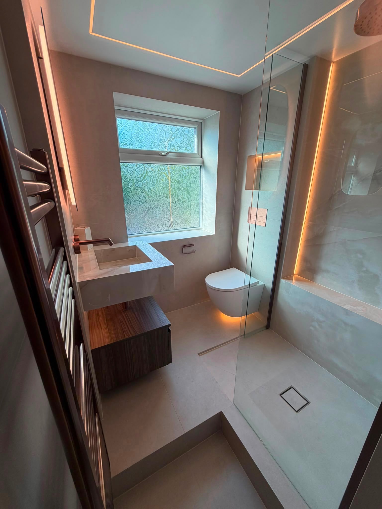 Shower room with warm cove lighting and a timber vanity